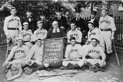 Brother Jasper seated with the Manhattan College baseball team in the 1880s, with players wearing ‘Jasper’ uniforms and holding an 1886 Collegiate New York April Games banner.