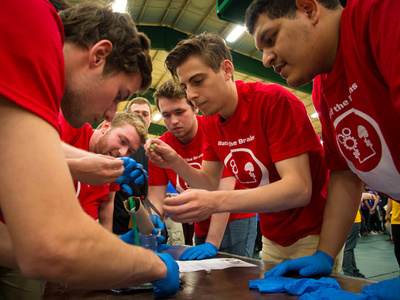 students gather around a table wearing matching t-shirts and gloves