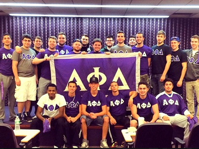 student members of the Alpha Phi Delta fraternity posing with their banner