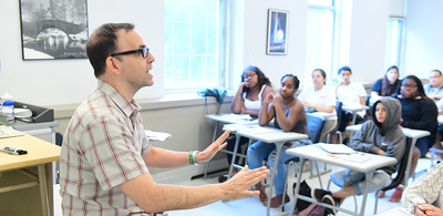 A professor teaches in front a classroom of students