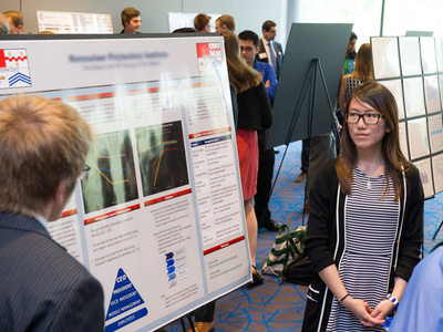 a student stands near a poster presentation at a conference