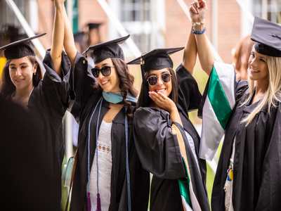 graduates in caps and gown pose together for a photo