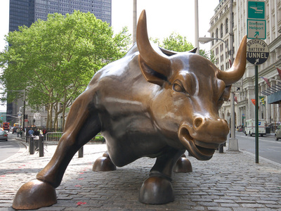 A large, brass bull statue on a city sidewalk