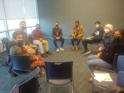 students sit on chairs in a circle inside a classroom