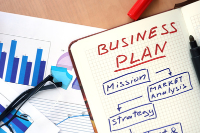 notebook open with the text "Business Plan" written on a page