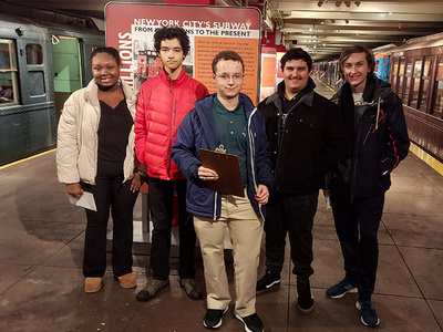 members of the train club stand near a subway platform