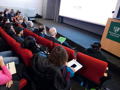an audience watches a film in a small theater
