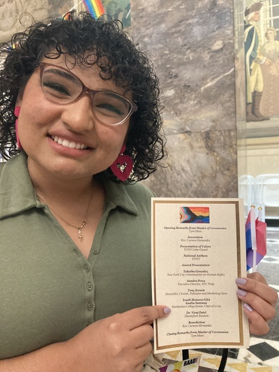 The Rainbow Jaspers President holding a program guide for a Pride event