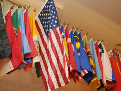 Flags of many countries hang on poles mounted to a wall