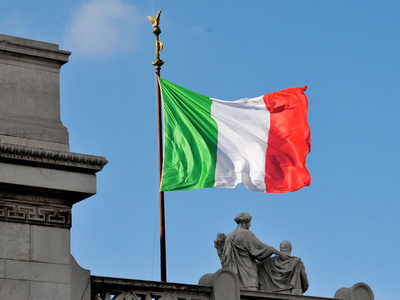 The Italian flag waving on a pole above a building