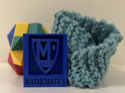 a knitted cuff, a geometric toy, and a printed emblem of the Manhattan University Mathematics department