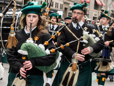 people play bagpipes in a city parade