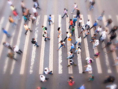 an aerial shot of people crossing a large street crosswalk