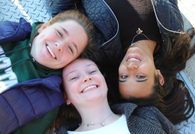 three women posing on the ground with their heads together