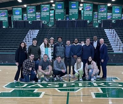 members of the sports media group pose together on a basketball court
