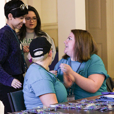 four people talk while at an information event table