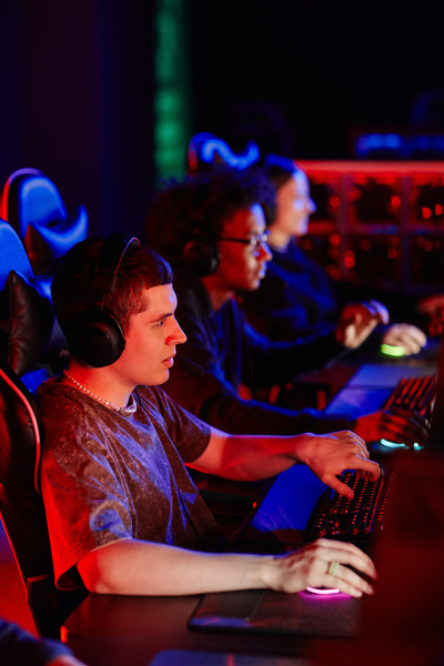 eSports team playing video games in row lit by neon light