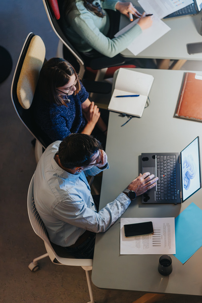 Overhead view of professional team working at a busy office desk with tech gadgets.