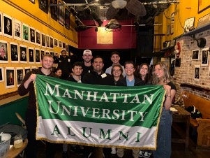 A group of young Manhattan University alumni posing together.