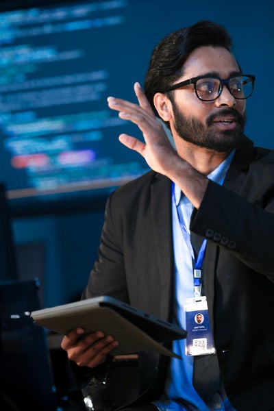 A data scientist holds a tablet in a command center.