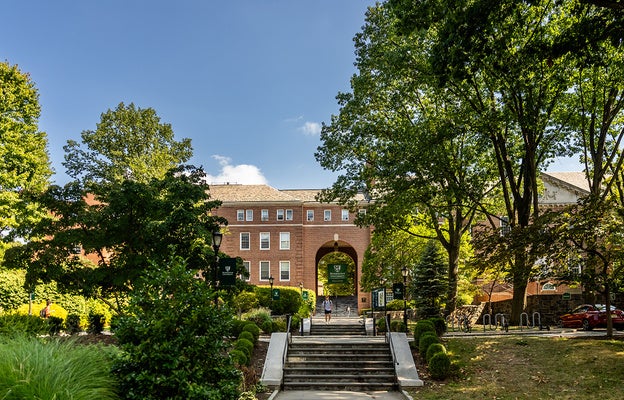 Front of campus with student walking down stairs at Manhattan University