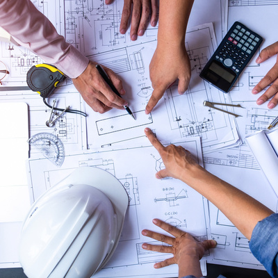 engineers pointing to building on blueprint and using laptop to drawing design building Project in office, construction concept. 