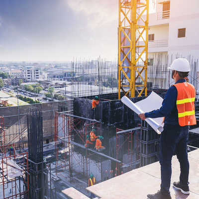 Civil architect engineer inspecting and working outdoors building side with blueprints. engineering and architecture concept.