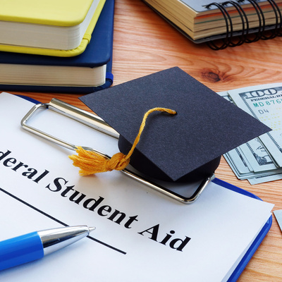 Federal student aid papers and small Square academic cap.