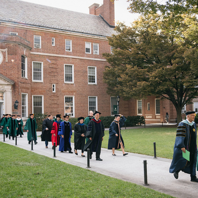 Academic procession walks across campus during Manhattan University inauguration.