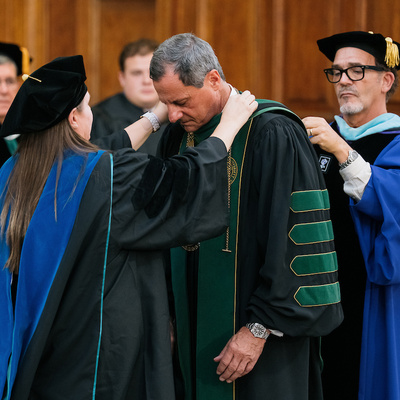 Academic official places ceremonial medallion on President Frederick Bonato during inauguration.