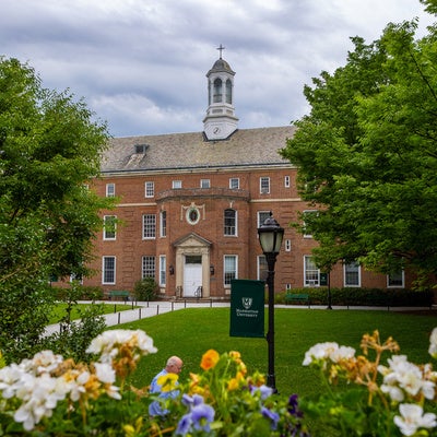 Picture of the Quad and Memorial Hall in the Summer with flowers.