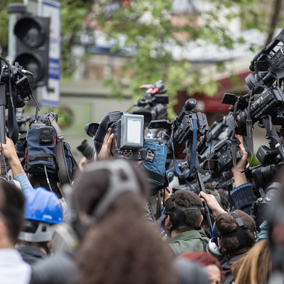 people standing in a group with cameras for a press conference