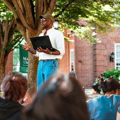 Manhattan University students and professor outside for a class lecture.