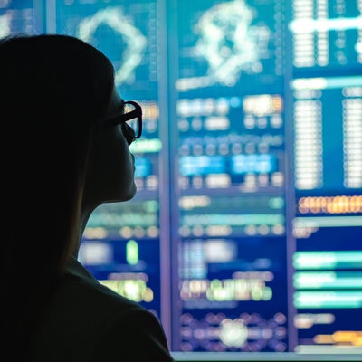 The businesswoman in glasses standing near the display looking at data and analytics