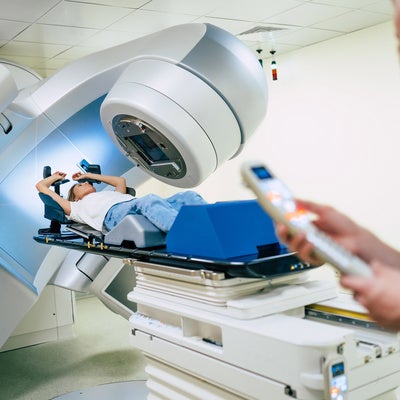 Cancer treatment in a modern medical private clinic or hospital with a linear accelerator. Professional doctors team working while the woman is undergoing radiation therapy for cancer
